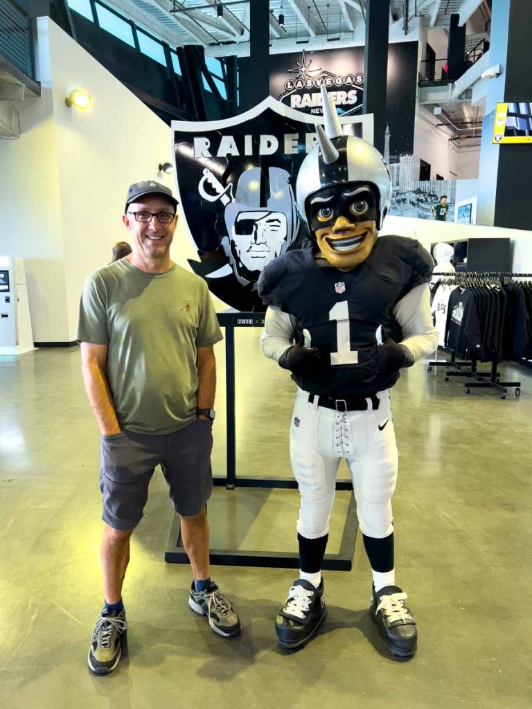Dan Brewer, owner of UltimateSportsRoadTrip.com, gets his picture taken with the Raider Rusher mascot before a game at Allegiant Stadium.