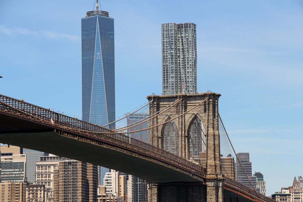 One World Trade Center stands behind the Brooklyn Bridge in New York City.