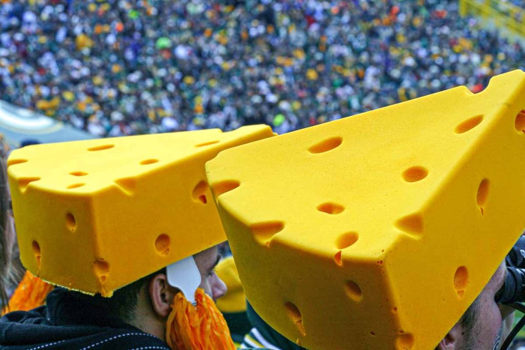 Two Green Bay Packer fans wear the iconic Cheesehead foam hats at a game at Lambeau Field.