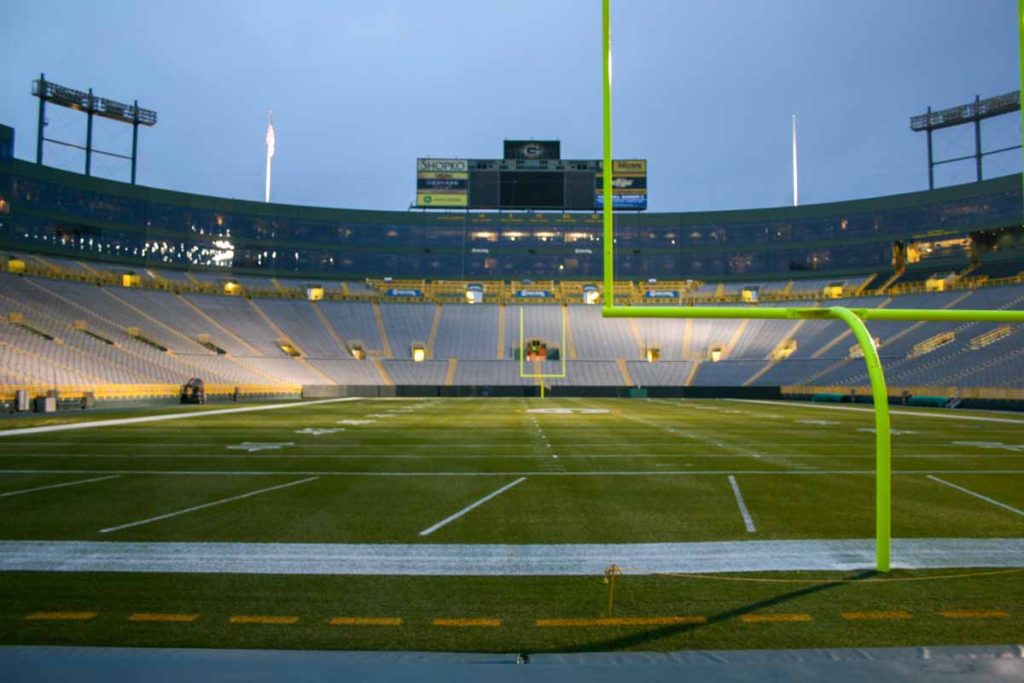 Lambeau Field as seen from the field level in the endzone, is lit up at dusk.