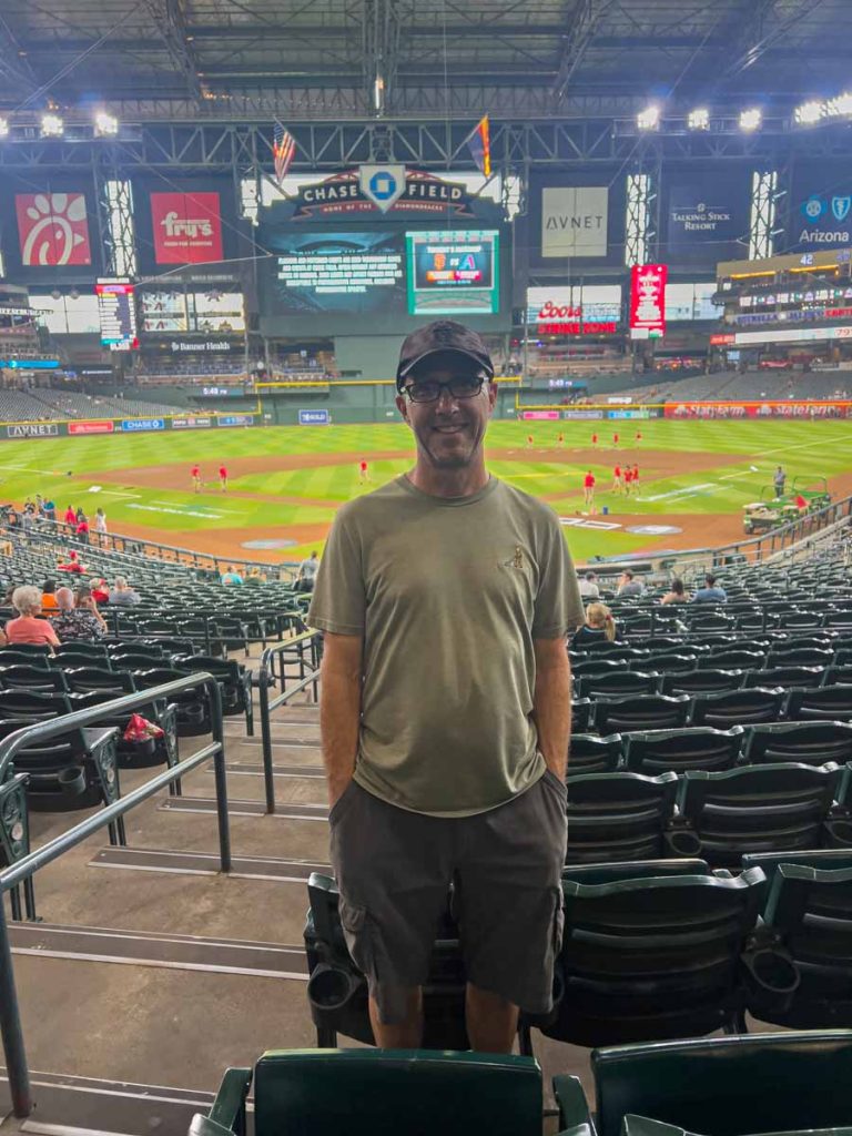 Dan Brewer, owner of the Ultimate Sports Road trip blog, stands at his Diamondbacks seat in Section 122 at Chase Field.