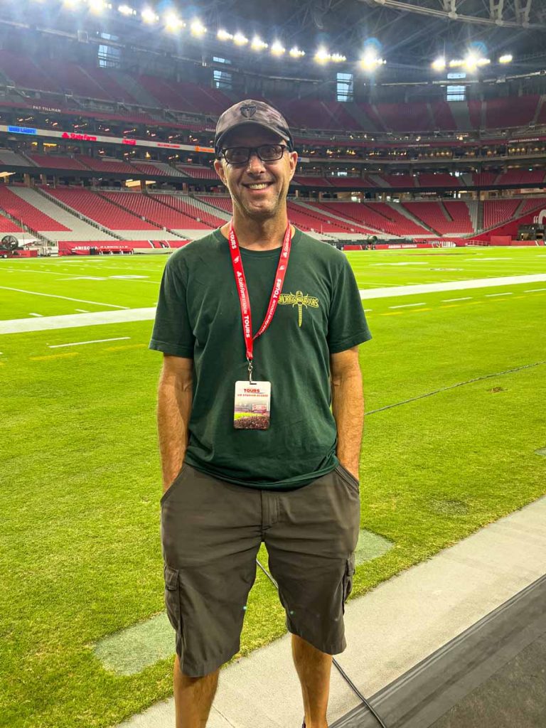 Dan Brewer stands next to the playing field while on a State Farm Stadium tour.